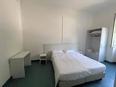 a white bedroom with a bed and a table and a chair at Green Park San Pancrazio in Rome