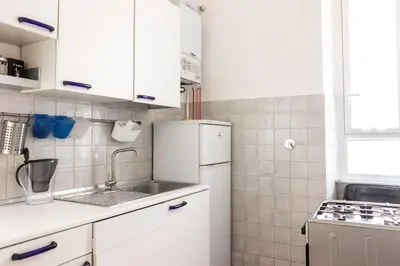 a white kitchen with a sink and a refrigerator at colosseo view apartment in Rome