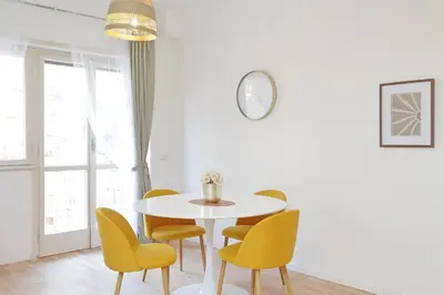 a white dining room with a white table and yellow chairs at Nature Flat in Rome
