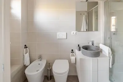 a white bathroom with a toilet and a sink at Gardenie House in Rome