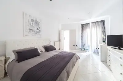 a white bedroom with a large bed and a television at Veneto Excelsior Suite in Rome