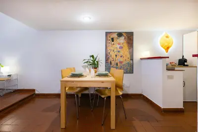 a dining room table with yellow chairs and a kitchen at Rome As You Feel - Designer two-level apartment in the heart of Trastevere in Rome