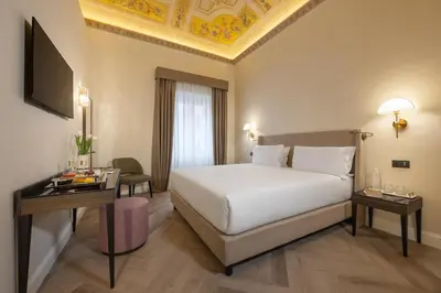 a bedroom with a large white bed and a table at BH Hotel in Rome
