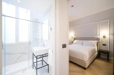 a white bedroom with a bed and a sink at BH Hotel in Rome