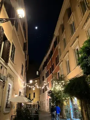 a group of people walking down a street at night at Amazing Terrace in Trastevere in Rome