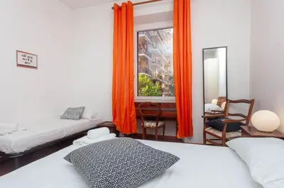 a bedroom with two beds and a window with orange curtains at Cami Vatican Apartment in Rome