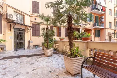 a bench in front of a building with palm trees at Cami Vatican Apartment in Rome