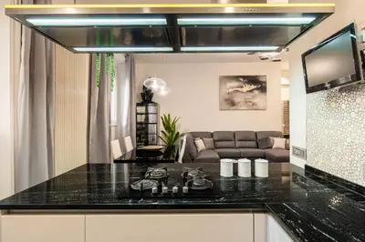 a kitchen with a black counter top and a couch at Dimora Colosseum Luxe - Jacuzzi & Private Patio in Rome