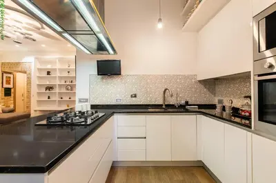 a kitchen with white cabinets and a black counter top at Dimora Colosseum Luxe - Jacuzzi & Private Patio in Rome
