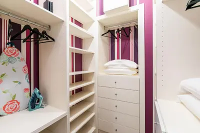a walk in closet with white drawers and pink walls at Dimora Colosseum Luxe - Jacuzzi & Private Patio in Rome