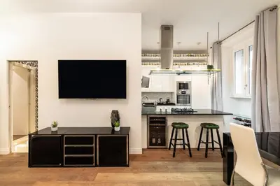 a kitchen and living room with a black counter and stools at Dimora Colosseum Luxe - Jacuzzi & Private Patio in Rome