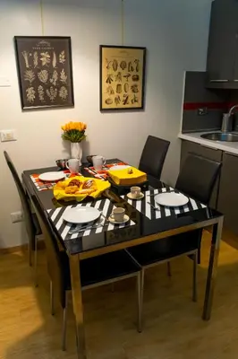 a black dining room table with chairs and a kitchen at Palestro Apartments in Rome