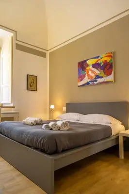 a bed in a bedroom with a painting on the wall at Palestro Apartments in Rome