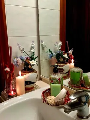 a bathroom sink with candles and flowers in a mirror at Casa Bianca in Rome