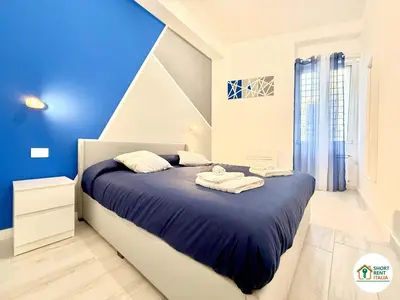 a bedroom with blue walls and a bed with towels on it at Re di Roma - Colosseo House in Rome