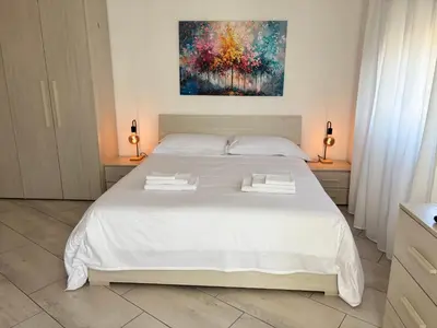 a white bed in a bedroom with a painting on the wall at Roma Elena in Rome