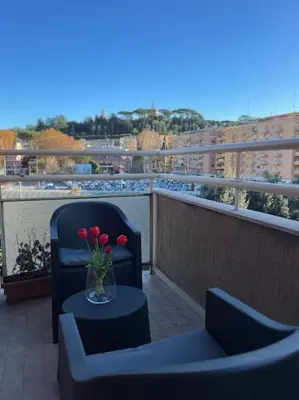 a vase of red flowers on a table on a balcony at Vatican Apartment Cipro in Rome