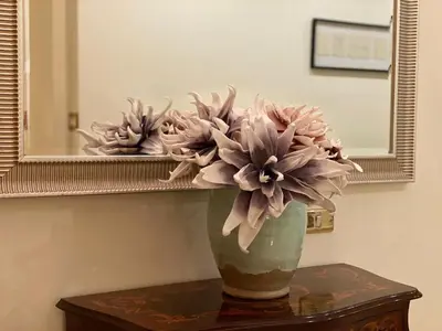 a vase of flowers on a table in front of a mirror at La Casa oltre il Parco in Rome