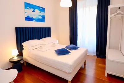 a bedroom with a white bed with two blue pillows on it at Prestige Crescenzio in Rome