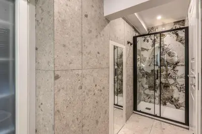 a walk in shower in a room with marble walls at Appartamento del Fico in Rome