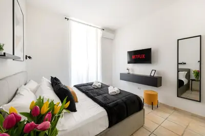 a bedroom with a bed and a tv and flowers at V HOME San Lorenzo in Rome