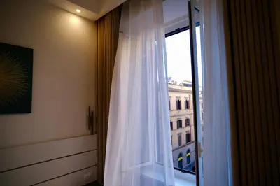 a window with a white curtain and a building at Maison Almo Guesthouse in Rome