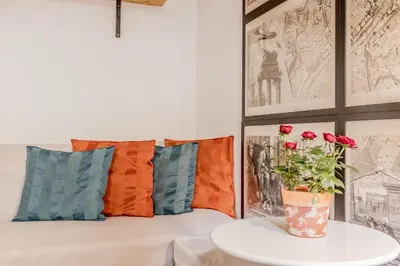a couch with pillows and a vase with flowers on a table at The ancient volute guest house in Rome