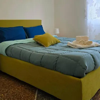 a large bed with blue and yellow sheets and pillows at Domus Passerini in Rome