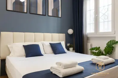 a bedroom with a large white bed with blue pillows at Imperium Luxury Suites - 100mt to Metro A, 5 min to center, pvt bathroom, A-C in Rome
