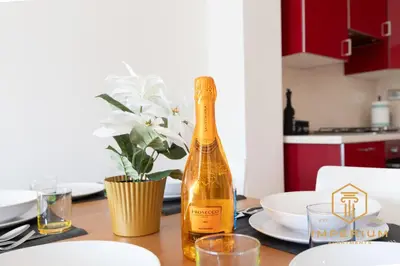 a bottle of champagne sitting on a table with plates at Imperium Deluxe Apt - 300mt to Metro B, 3 bedrooms, Panoramic view, A-C in Rome
