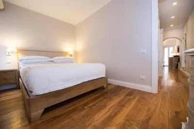 a bedroom with a bed with white sheets and wooden floors at Casa Belsiana in Rome