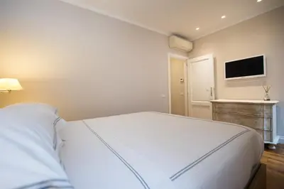 a bedroom with a white bed and a flat screen tv at Casa Belsiana in Rome