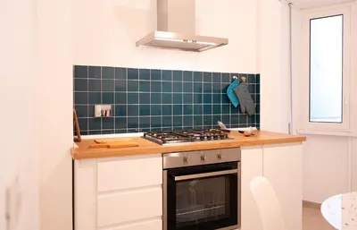 a kitchen with a stove and a green tiled wall at Vatican Fiore apartment in Rome