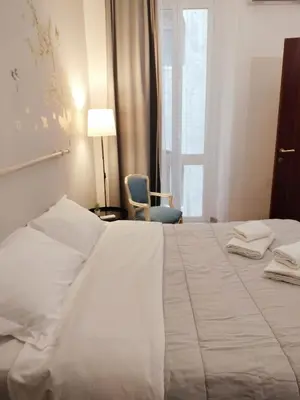 a large white bed in a hotel room with a chair at The Stay in Rome