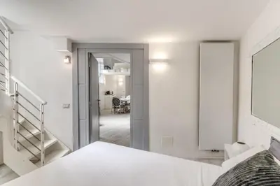 a bedroom with a white bed and a staircase at Elegant flat in the Historic Rome near Colosseum! in Rome