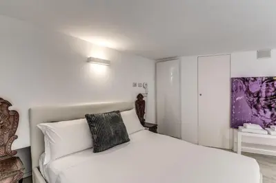 a white bedroom with a bed and a painting on the wall at Elegant flat in the Historic Rome near Colosseum! in Rome