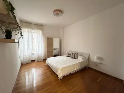a white bedroom with a bed and a large window at 5Piano Ascensore Near Vaticano Ideale per Famiglie in Rome