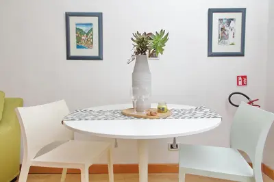 a white dining room table with white chairs and a vase at San Pietros Flat by DomusDimore in Rome