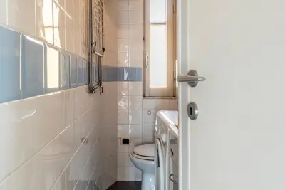 a white bathroom with a toilet and a window at GuestHost - Bright and roomy apartment in Flaminio district in Rome