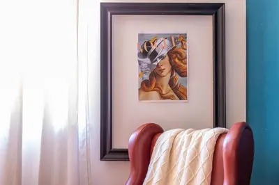 a picture hanging on a wall with a red chair at iFlat Charming Vintage Apartment in Esquilino in Rome