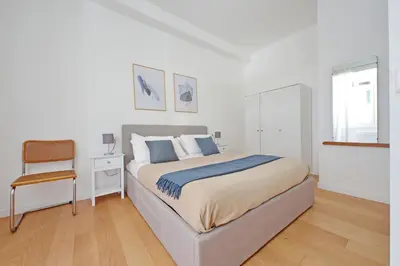 a white bedroom with a bed and a chair at YCH-Delightful flat near San Giovanni in Rome