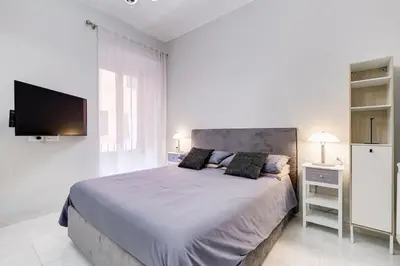 a white bedroom with a large bed and a flat screen tv at Vatican Escape in Rome
