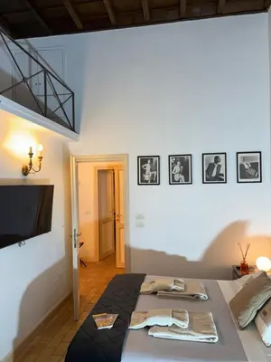 a room with a bed with a television and pictures on the wall at La Dimora a Roma antica in Rome