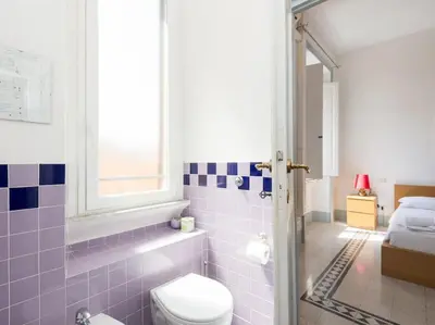 a bathroom with a toilet and a bed and a window at Vatican Comfortable Sunny Apartment in Rome