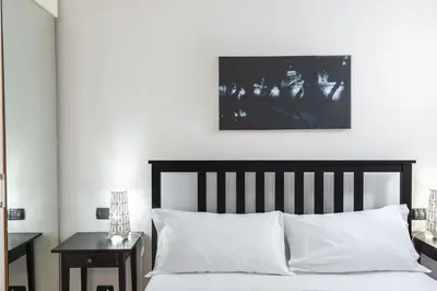 a bedroom with a bed with white sheets and a picture on the wall at Elegantis Purificazione Suite Apartment in Rome