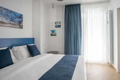 a bedroom with a large bed with blue curtains and a window at Hezio Guest House in Rome