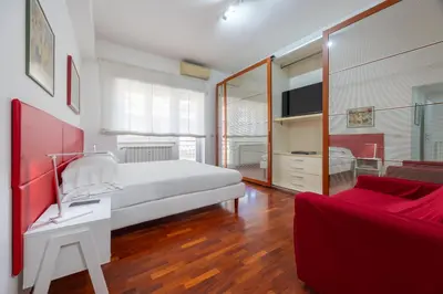 a bedroom with a white bed and a red couch at Vaticano84 Gemelli in Rome