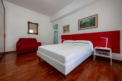 a bedroom with a white bed and a red chair at Vaticano84 Gemelli in Rome