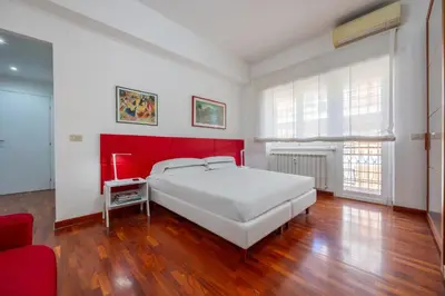 a bedroom with a white bed and a red headboard at Vaticano84 Gemelli in Rome