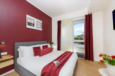 a bedroom with a bed with red walls and a window at Tolu Relais in Rome